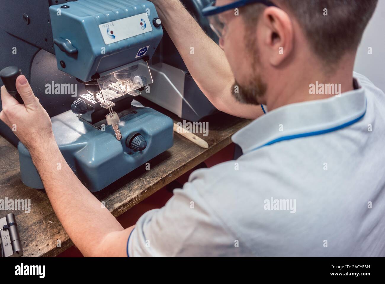 Locksmith cutting key with his machine Stock Photo
