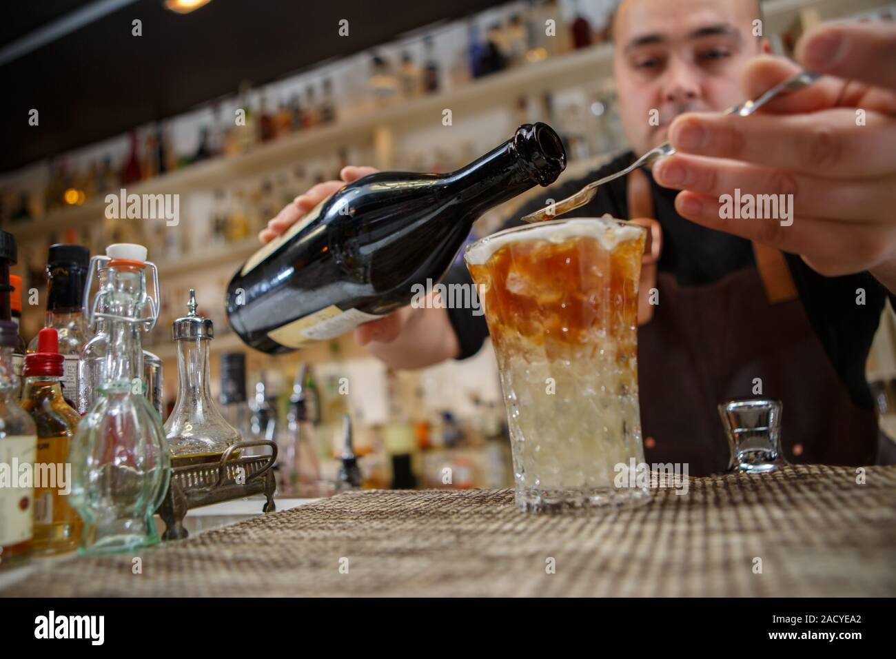 Bartender pouring cocktail into glass at the bar Stock Photo