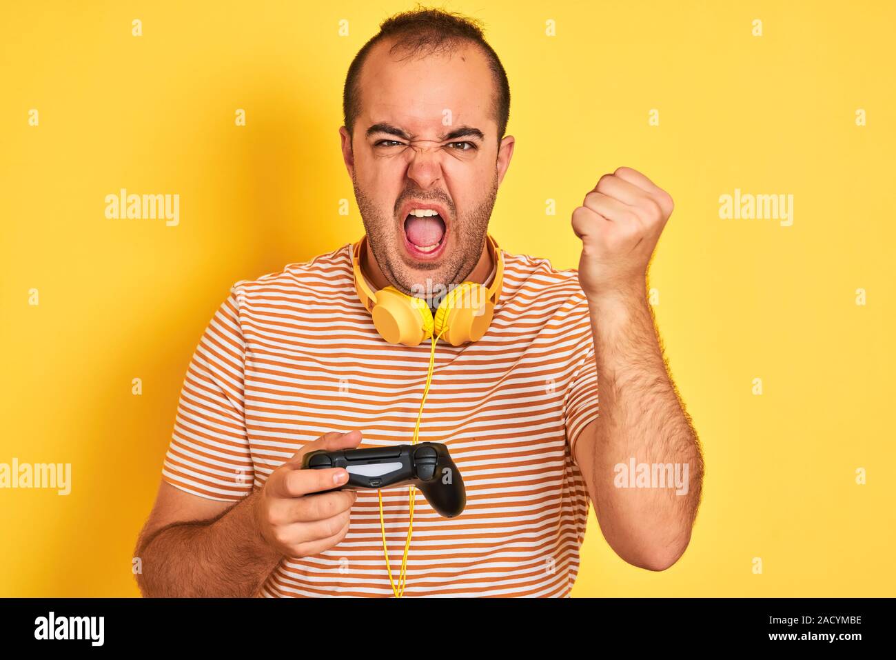 Young gamer man playing video game using headphones over isolated