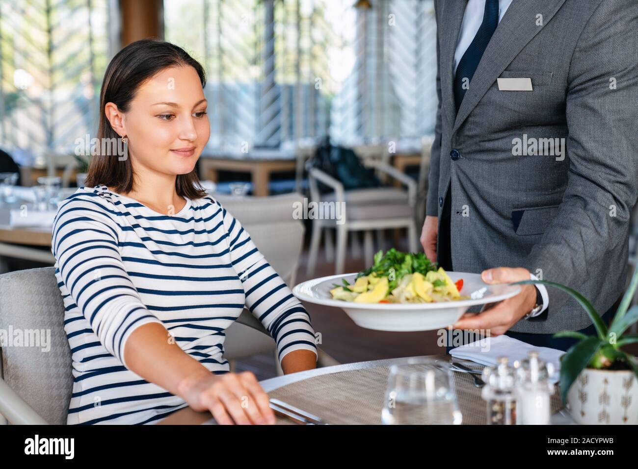 Young woman get served from waiter for a lunch in a elagance restaurant. Stock Photo