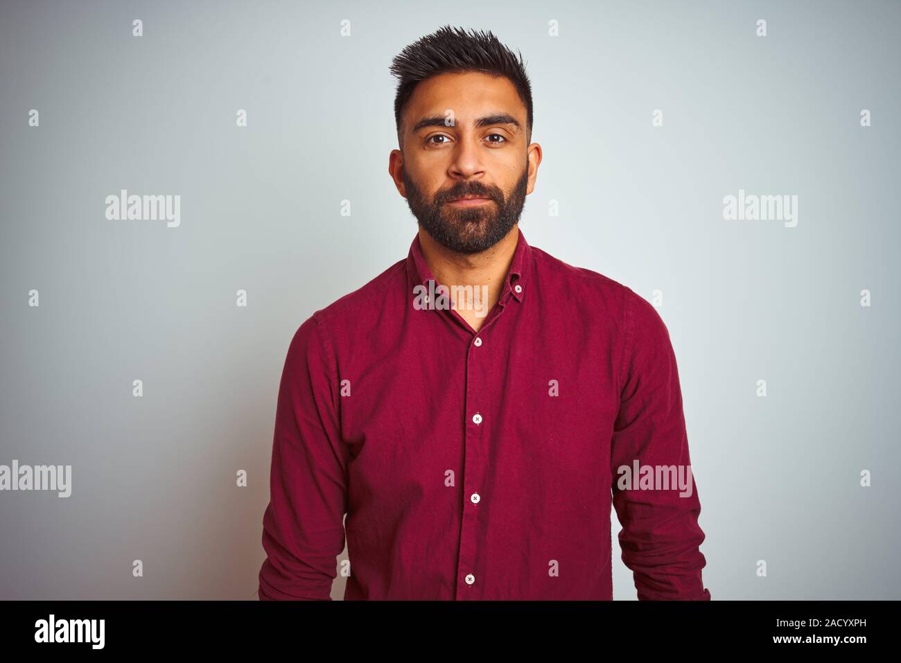 Young Indian Man Wearing Red Elegant Shirt Standing Over Isolated