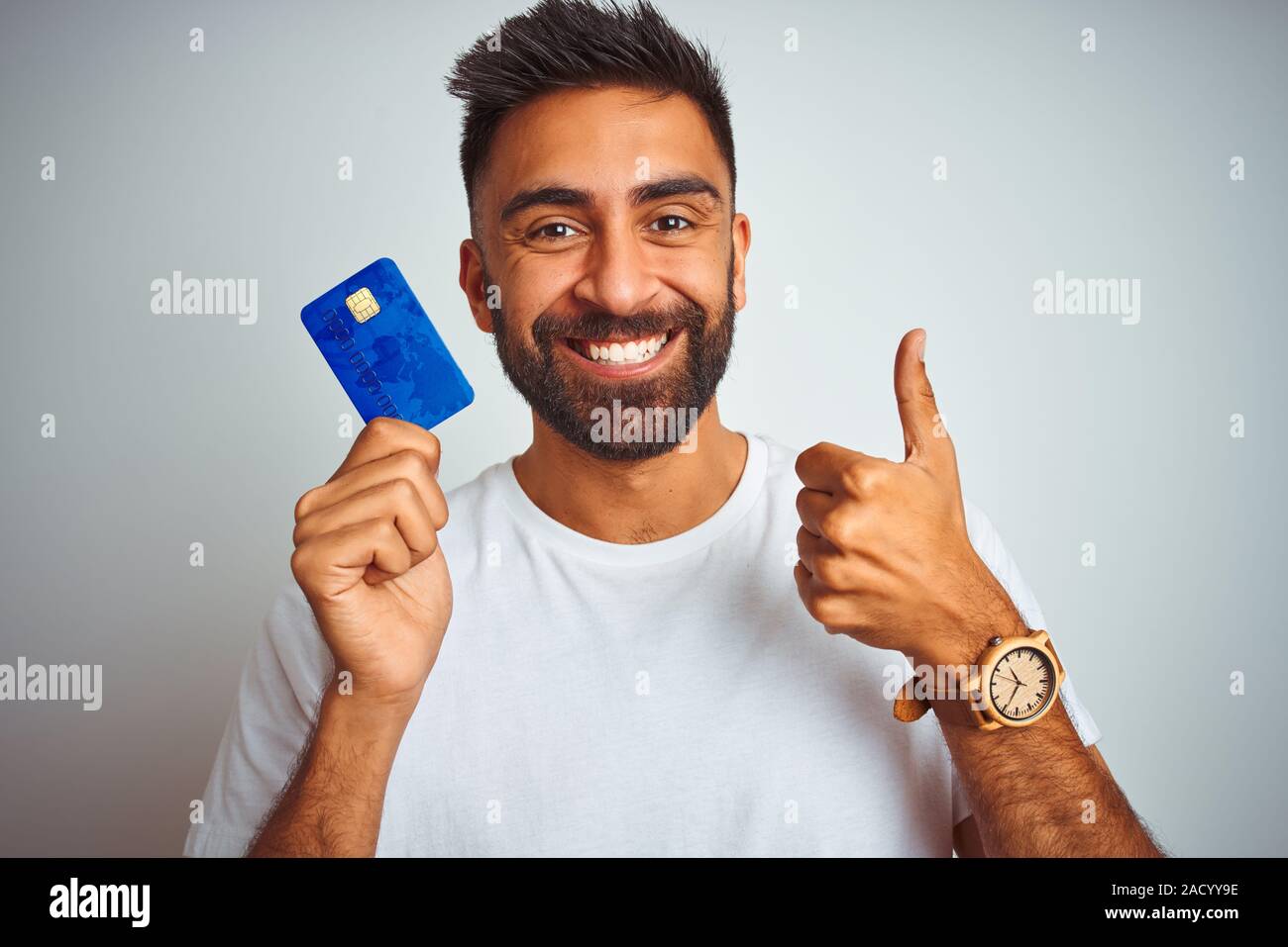 Young indian customer man holding credit card standing over isolated ...