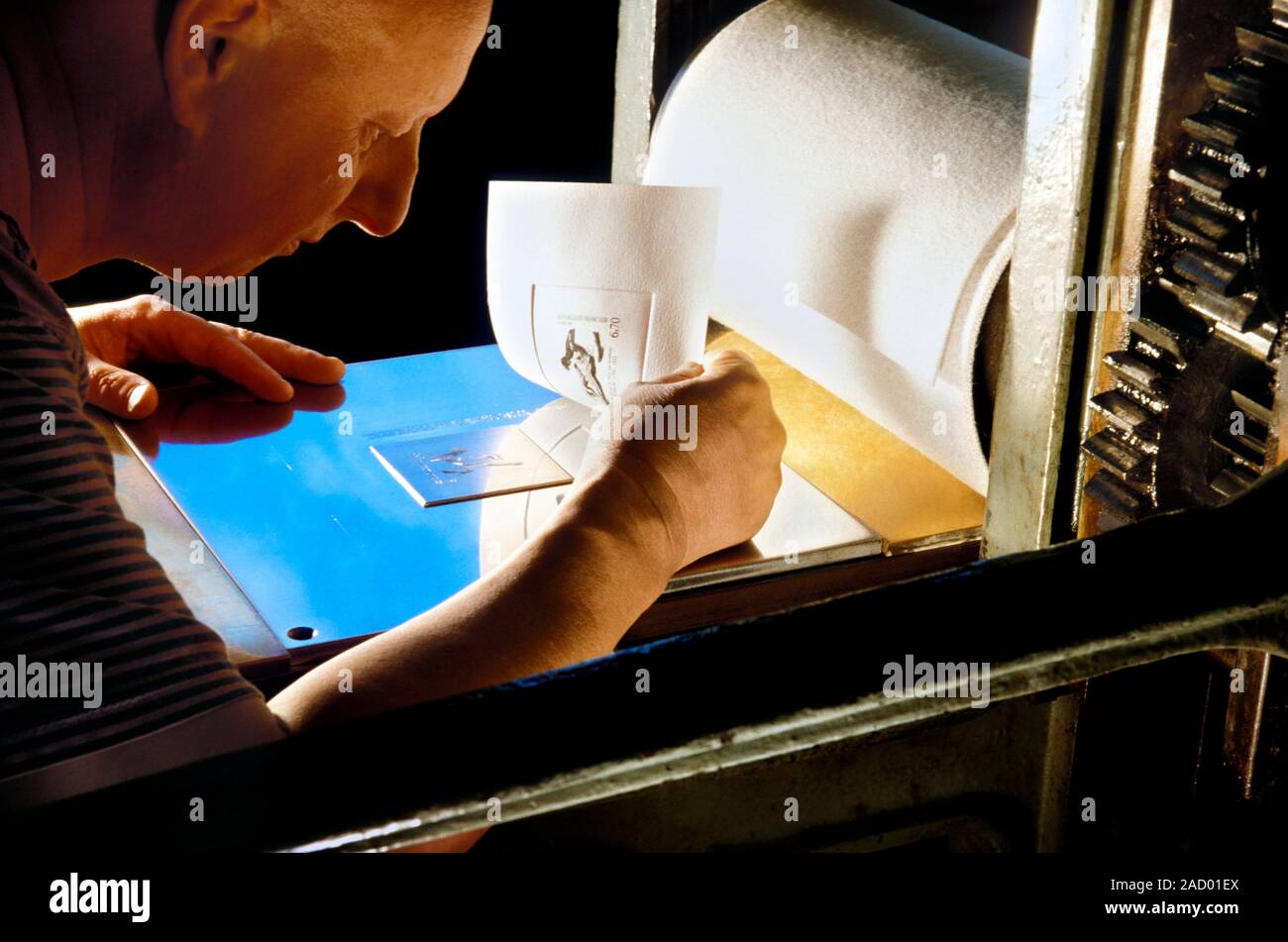 Intaglio printmaking. Printer using an incised metal plate and paper to