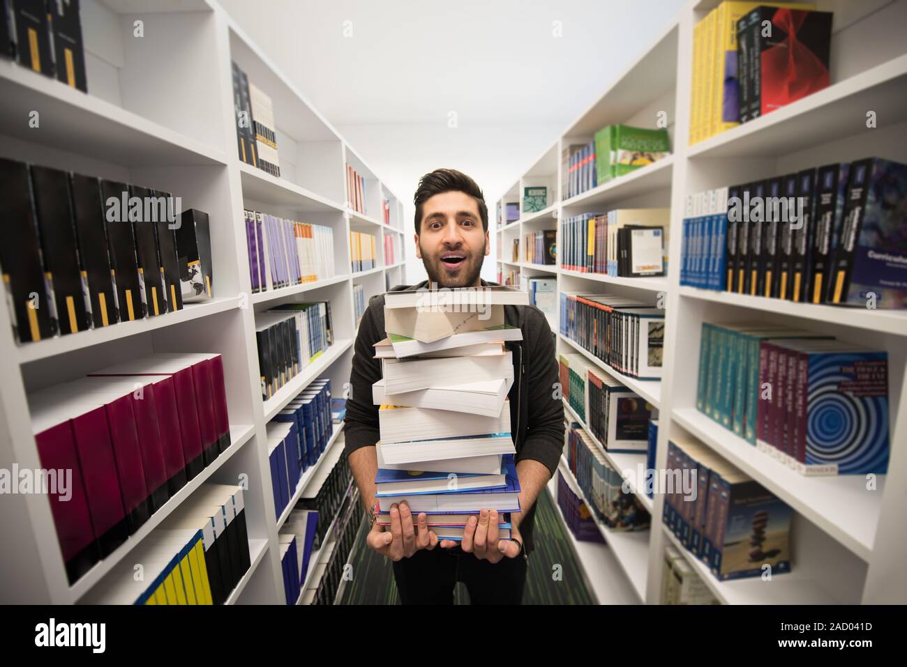 Student holding lot of books in school library Stock Photo - Alamy