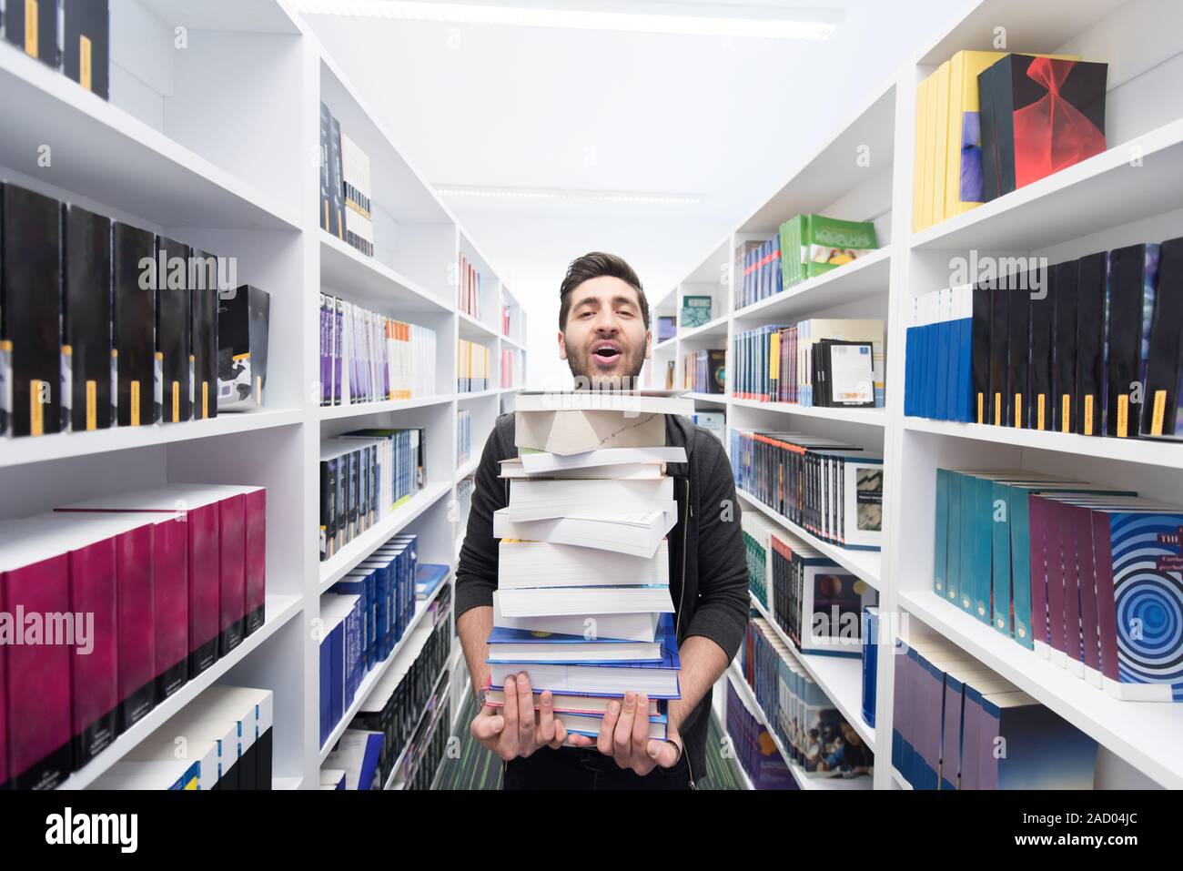 Student holding lot of books in school library Stock Photo - Alamy