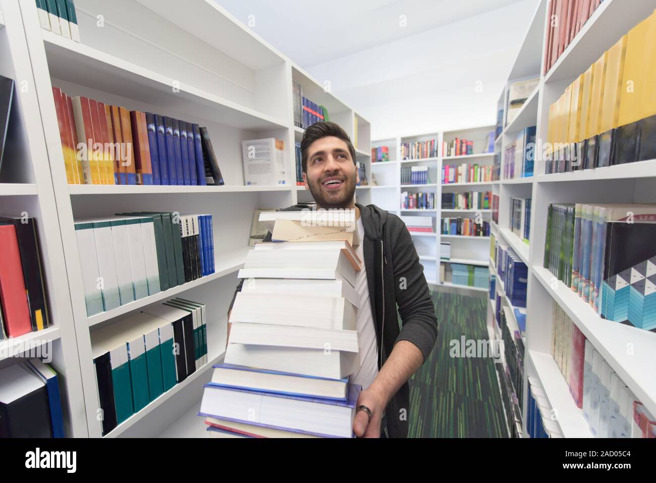 Student holding lot of books in school library Stock Photo - Alamy