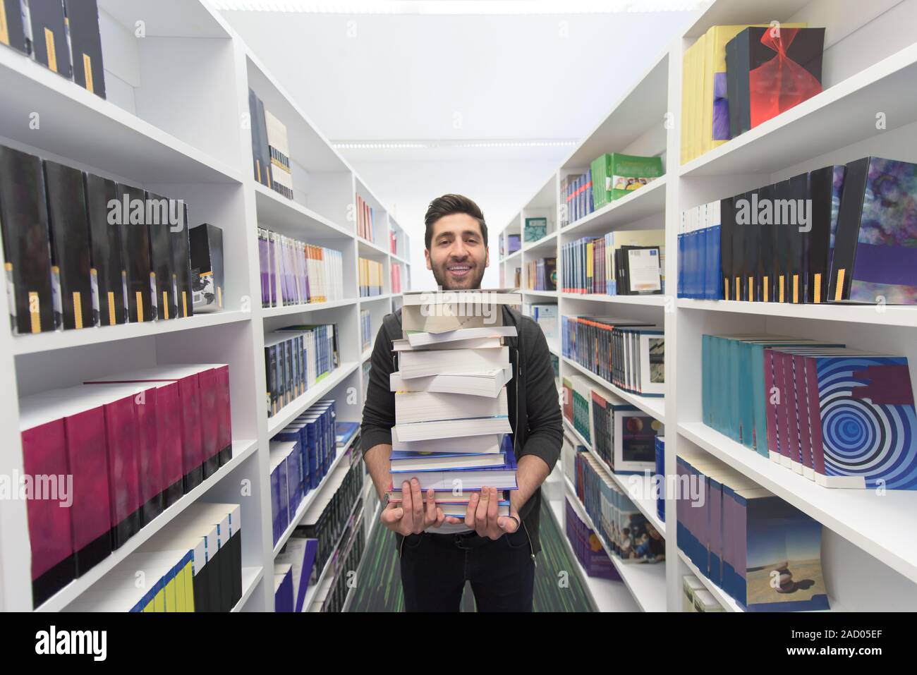 Student holding lot of books in school library Stock Photo - Alamy