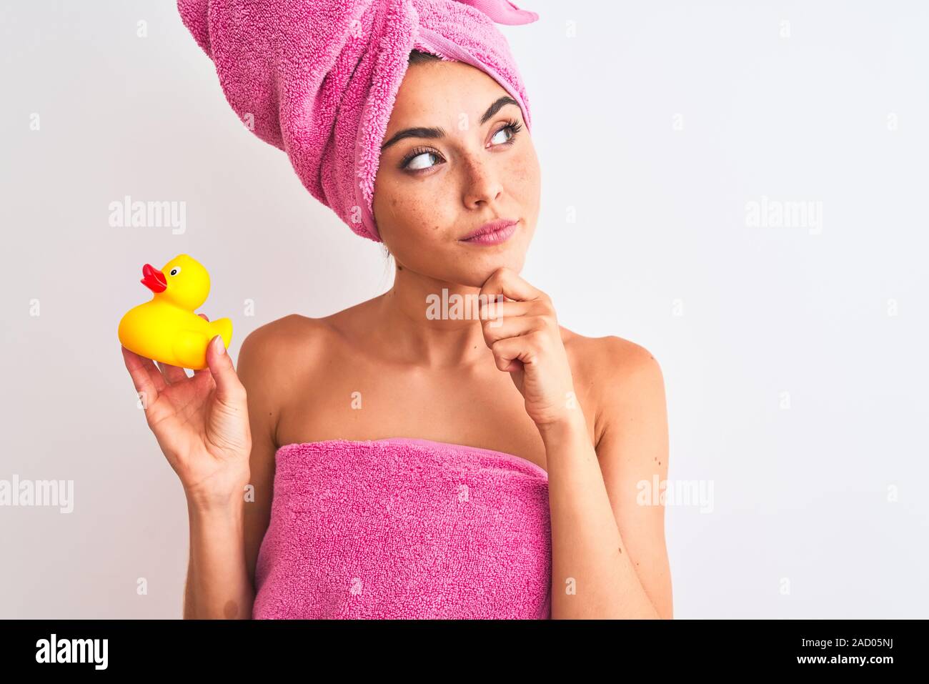 Young beautiful woman wearing shower towel holding duck over 