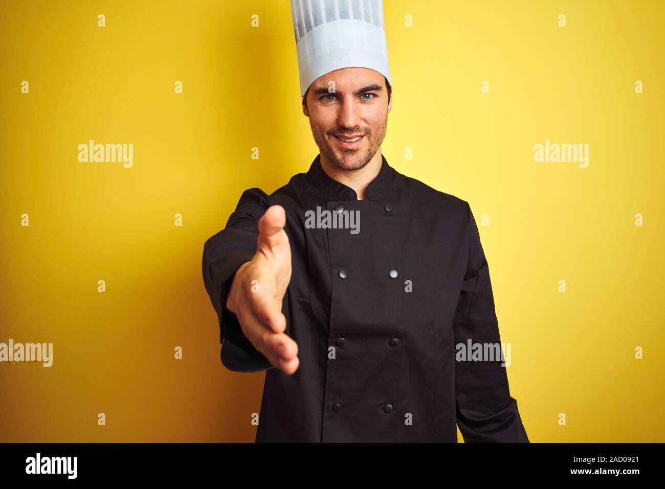 Handshake Chef Young chef man wearing uniform and hat standing over isolated yellow ...