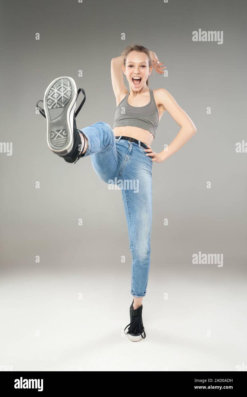 Cheerful young woman kicking with leg in sneakers Stock Photo - Alamy
