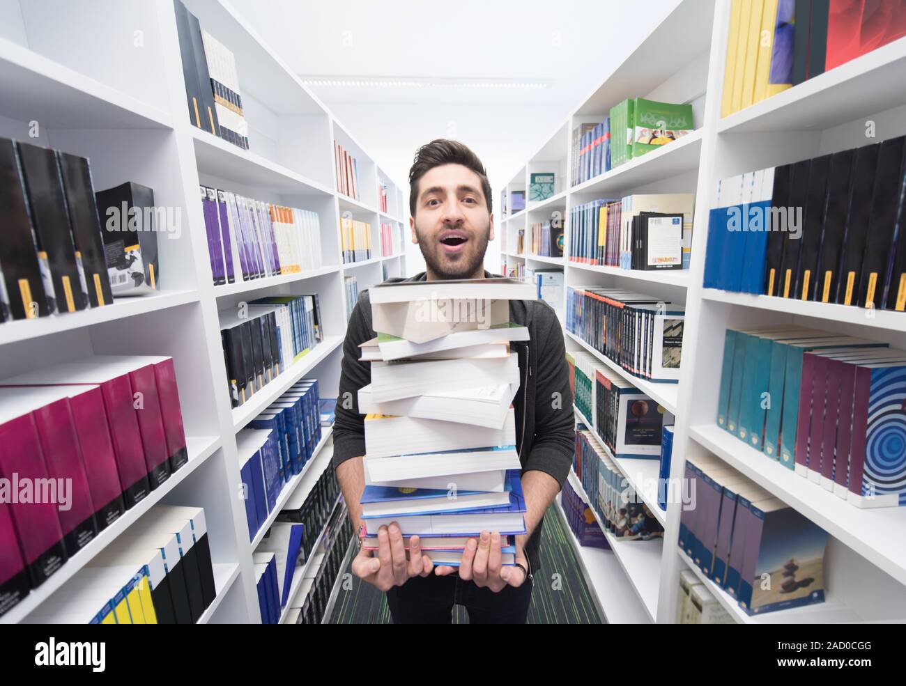 Student holding lot of books in school library Stock Photo - Alamy