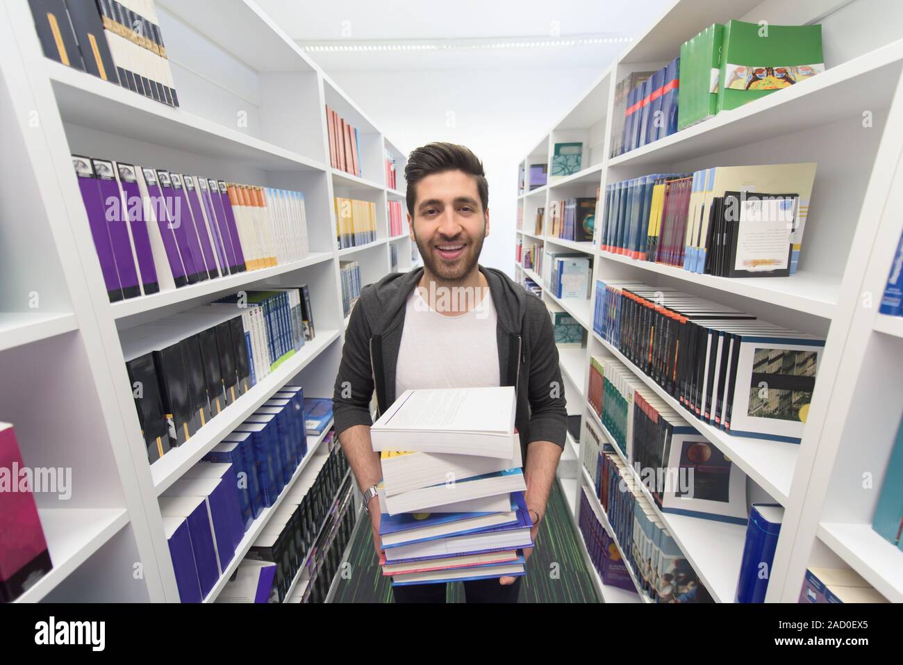 Student holding lot of books in school library Stock Photo - Alamy