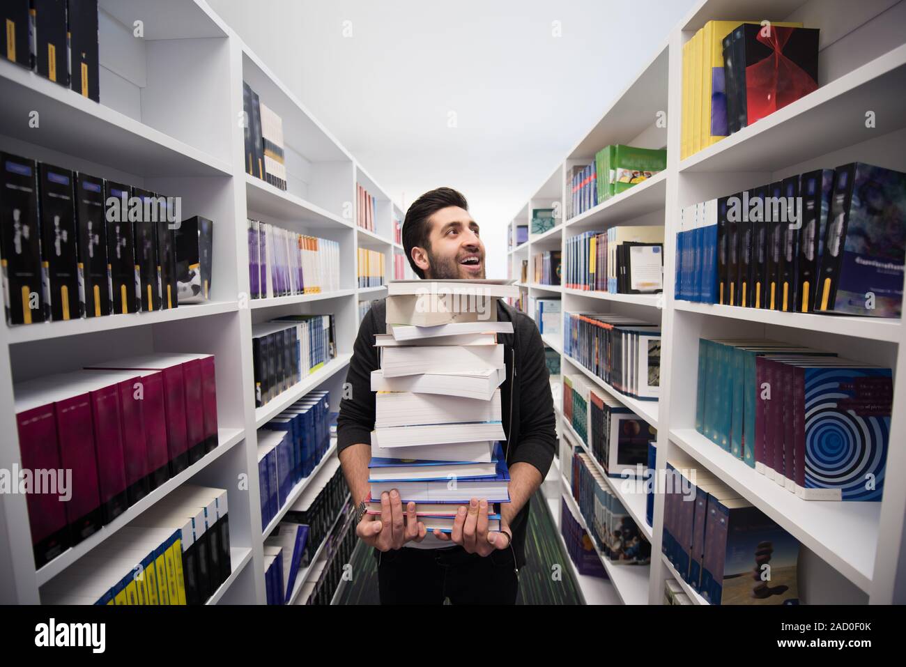 Student holding lot of books in school library Stock Photo - Alamy