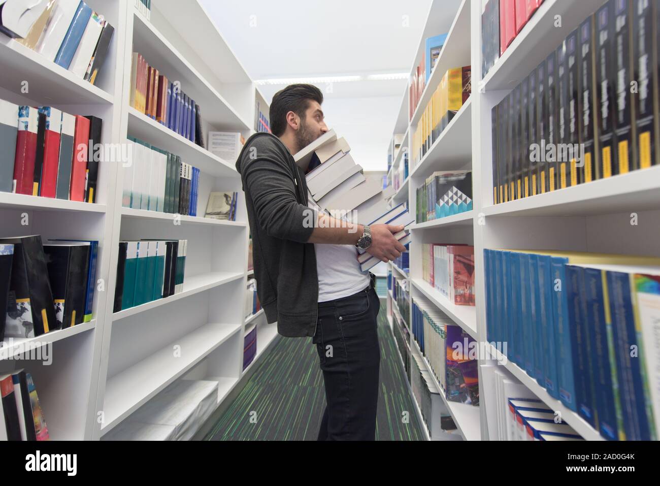 Student holding lot of books in school library Stock Photo - Alamy