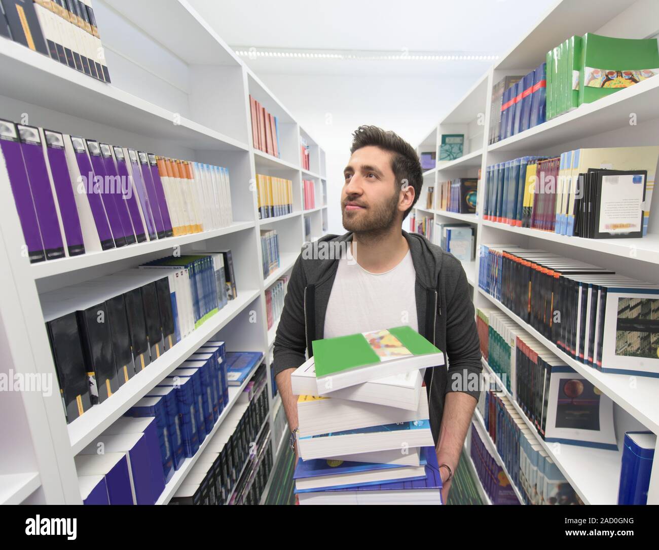 Student holding lot of books in school library Stock Photo - Alamy