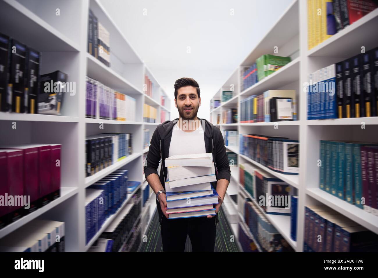 Student holding lot of books in school library Stock Photo - Alamy