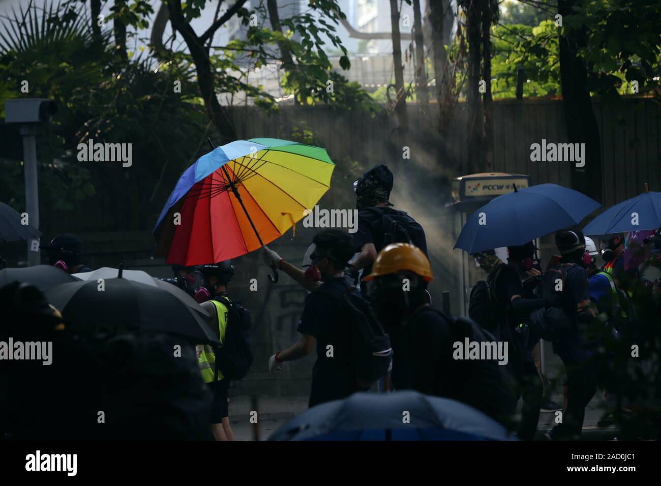 Hong Kong. 20th Oct 2019. A black-clad protestor can be seen using a rainbow umbrella as a makeshift shield in front of a police station. Stock Photo