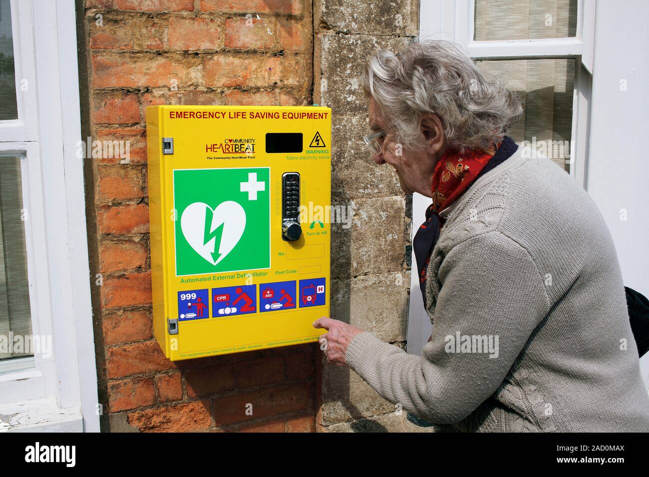 Public defibrillator. Woman looking at a defibrillator mounted on a wall in a public place. A