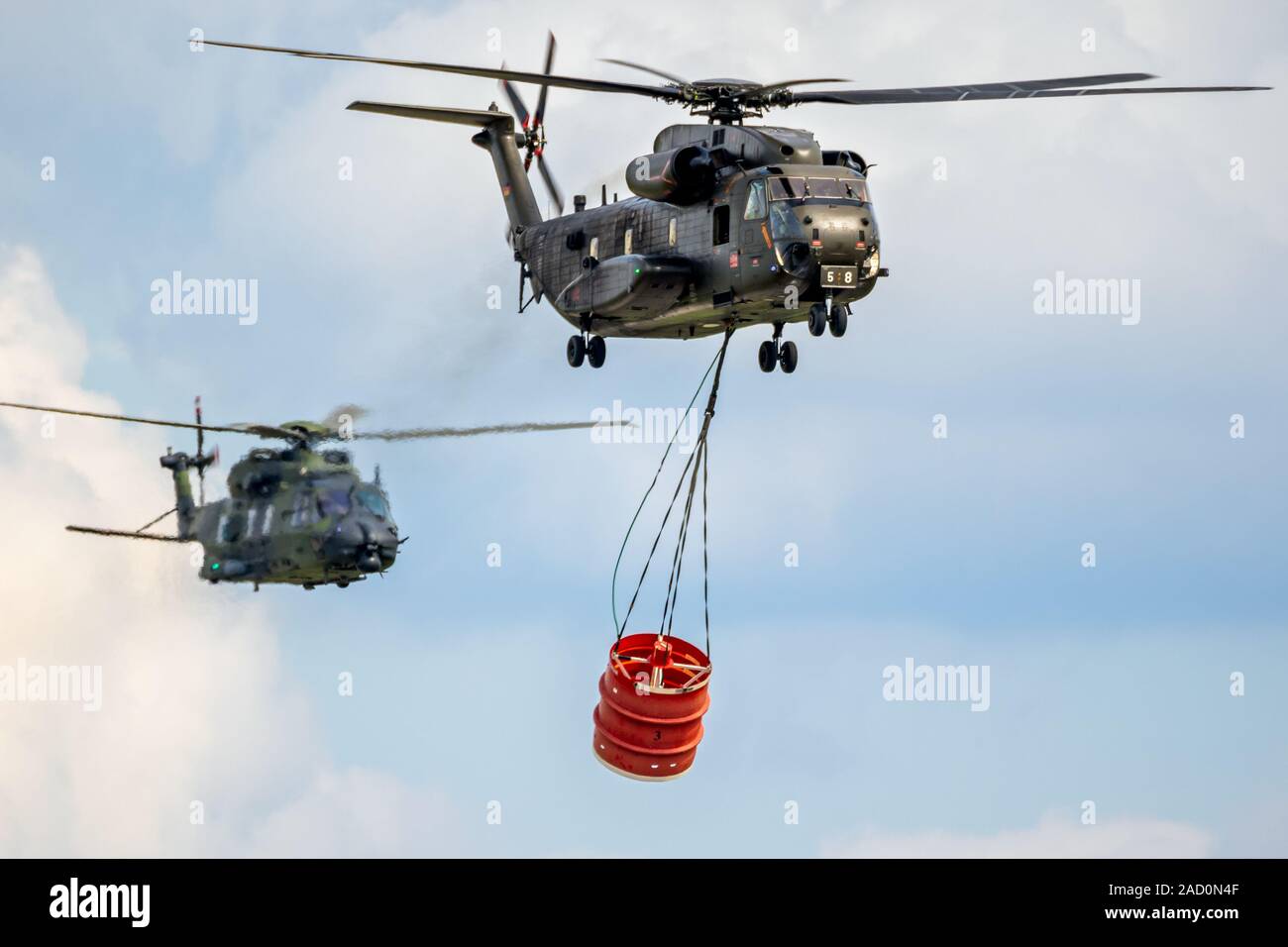 BERLIN - APR 27, 2018: German Air Force NH90 and CH-53 Stallion helicopter with a bambi-bucket during an aerial fire fighting demonstration at the Ber Stock Photo