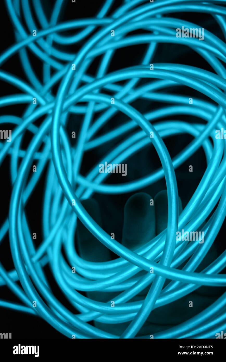 Chaotic sky blue wires, light guide electroluminescent wires, electroluminescence are located on a glossy black surface. Stock Photo