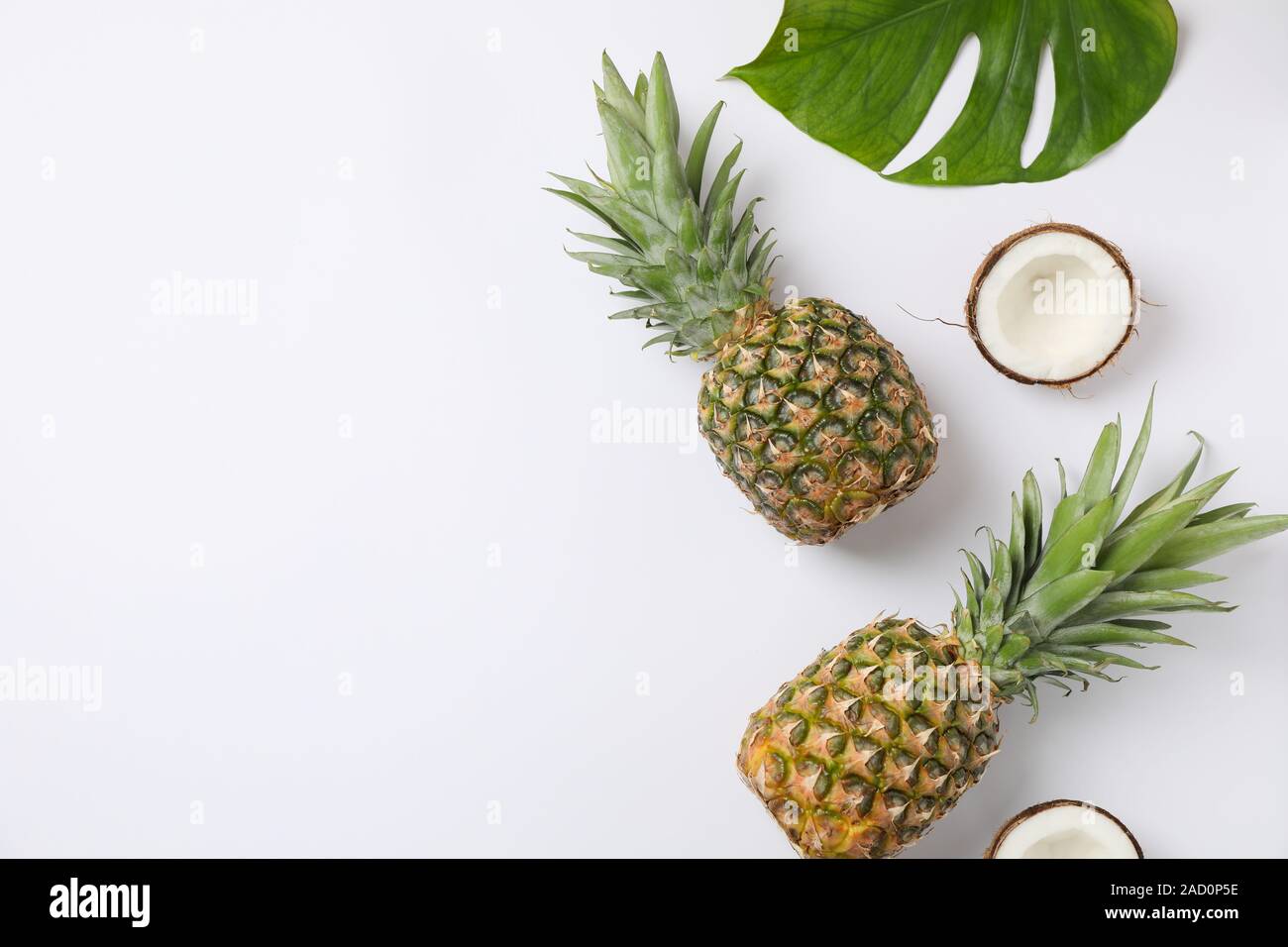 Pineapples, coconuts and palm leaves on white background, space for text Stock Photo