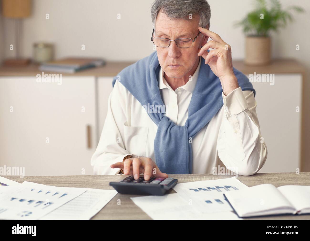 Thoughtful Elderly Businessman Using Calculator Working In Office Stock Photo