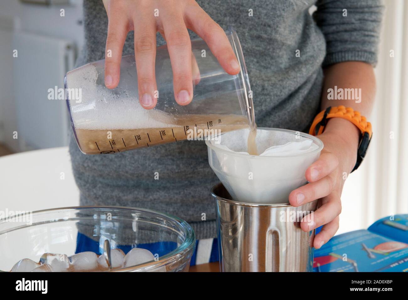 DNA extraction experiment. Teenage boy pouring processed banana through