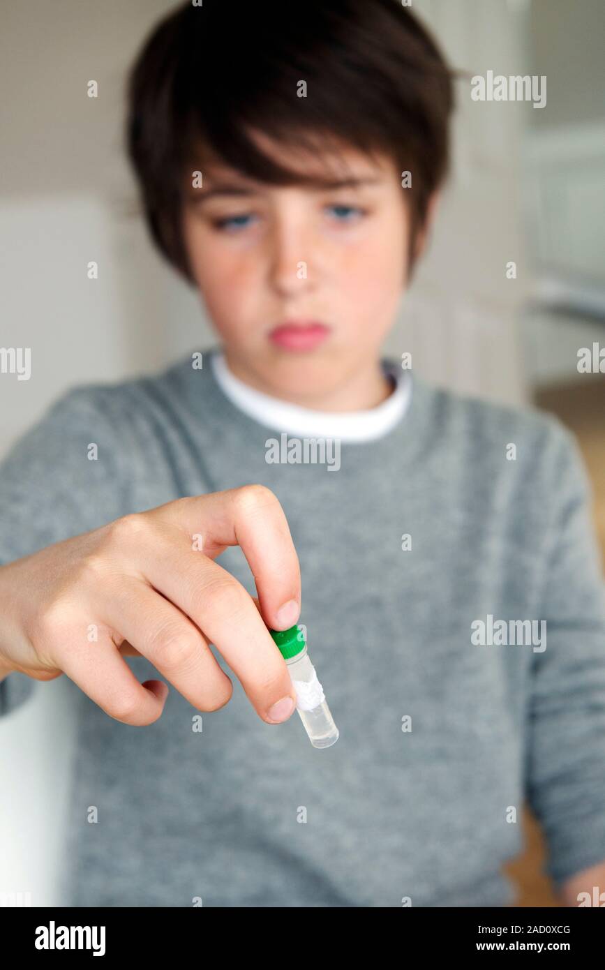 DNA extraction experiment. Teenage boy shaking the sample vial after
