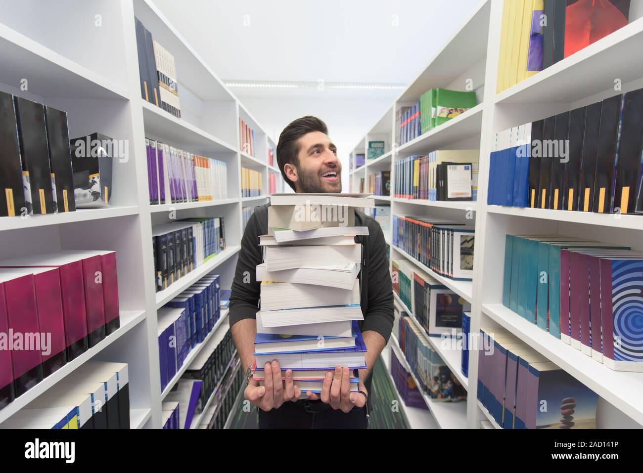 Student holding lot of books in school library Stock Photo - Alamy