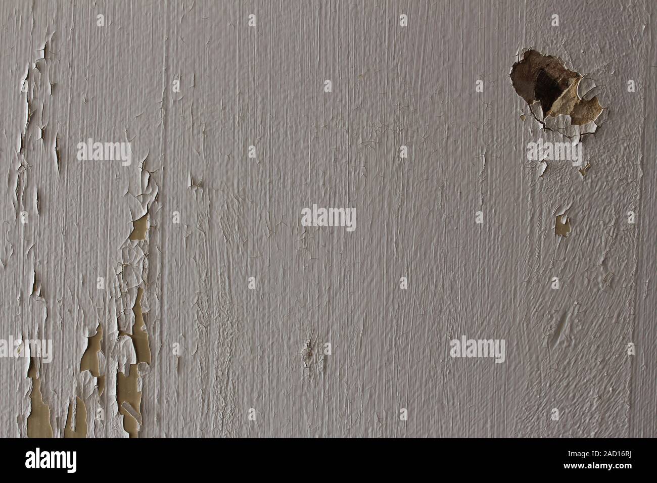 Wall with cracked white paint peeling off and a hole Stock Photo