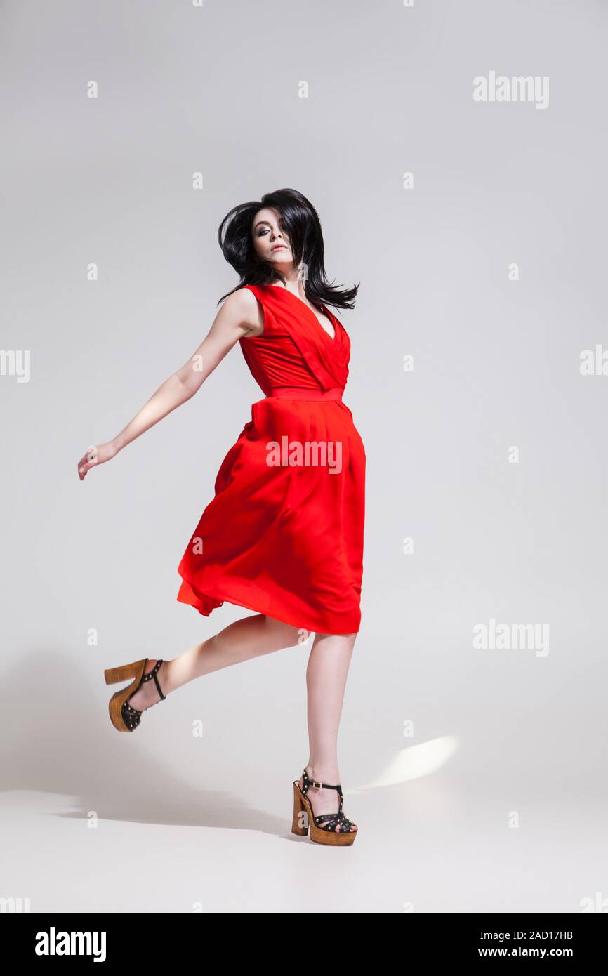 Black-haired woman twisting in red dress Stock Photo