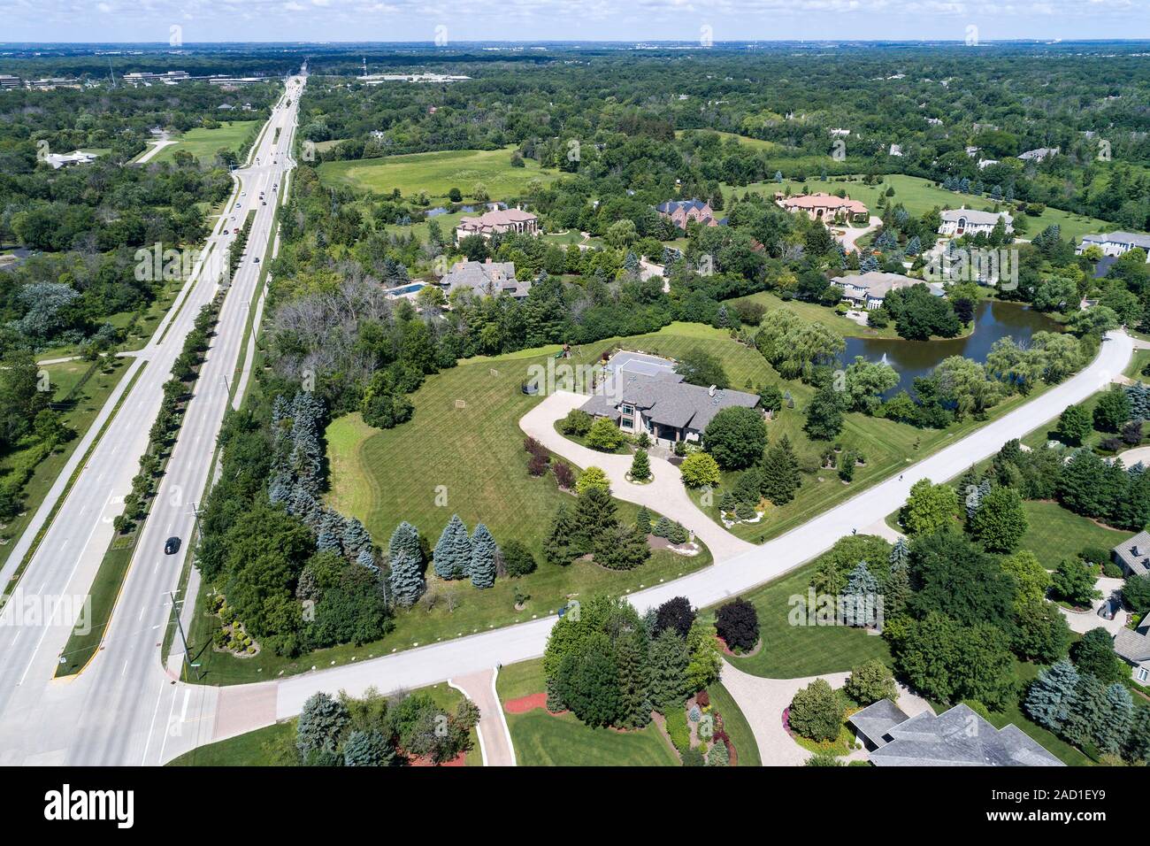 Aerial view of a luxury neighborhood with mature trees and a pond in a