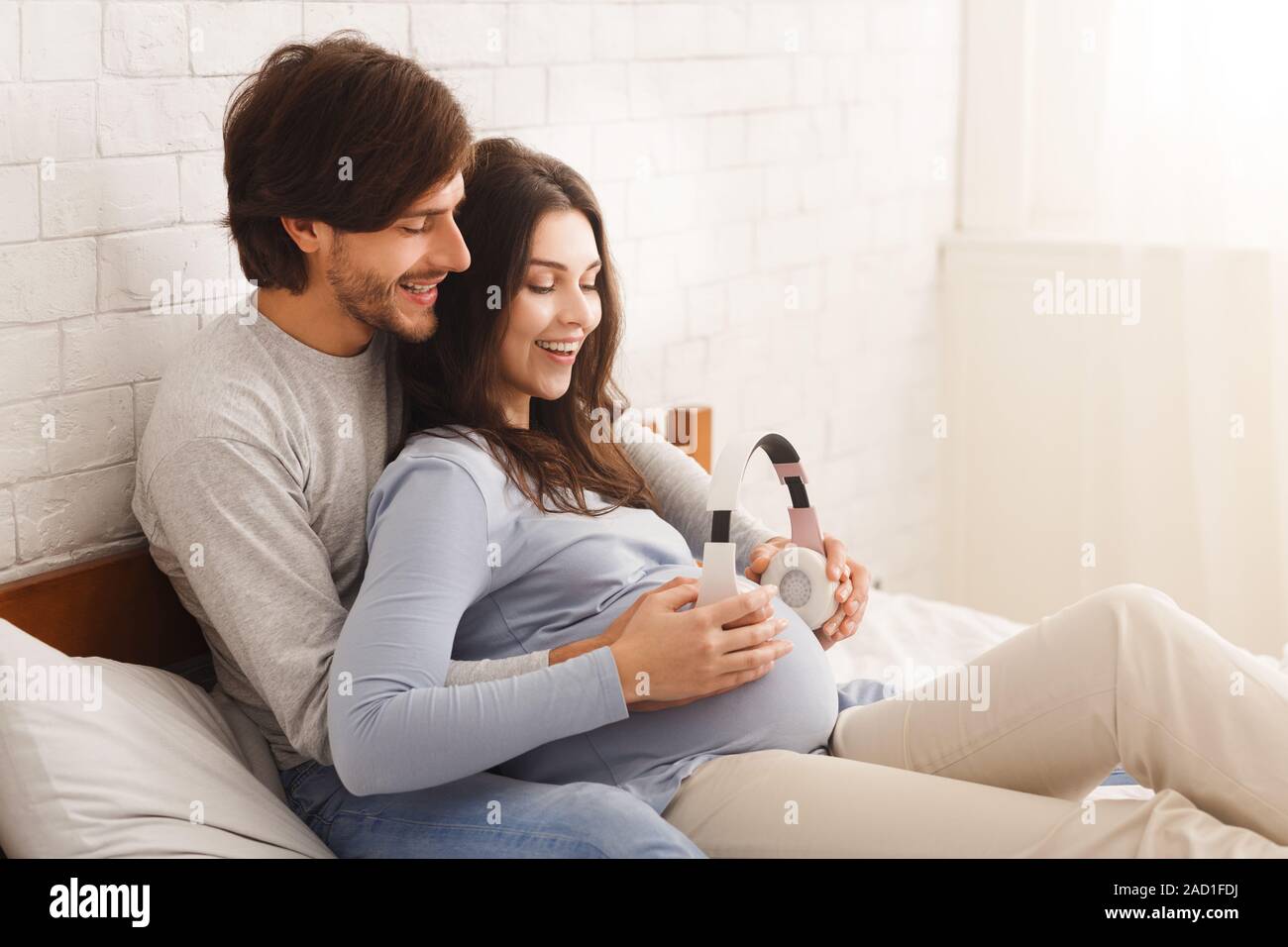Pregnant woman music lover put the headphones on her belly to let Rebecca  enjoy the music she likes. Girl waiting for a baby keeps headphones on her  Stock Photo - Alamy