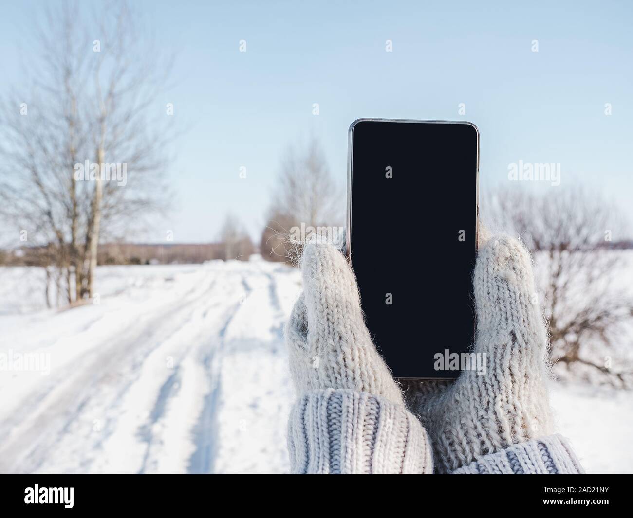 Woman Holding A Mobile Phone In Woolen Mittens Stock Photo Alamy