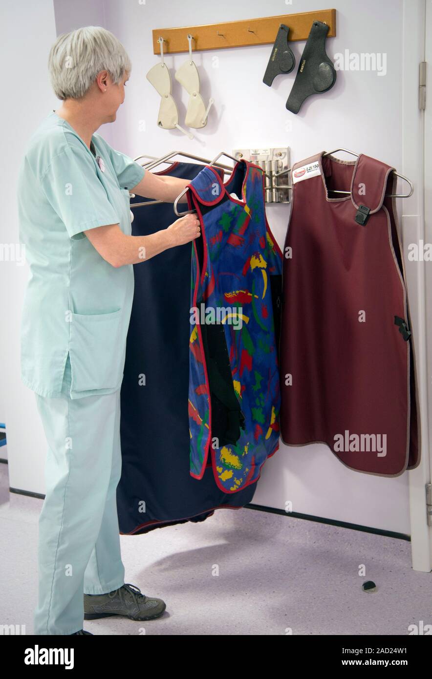 Hospital radiographer with lead apron. Lead aprons are used to protect