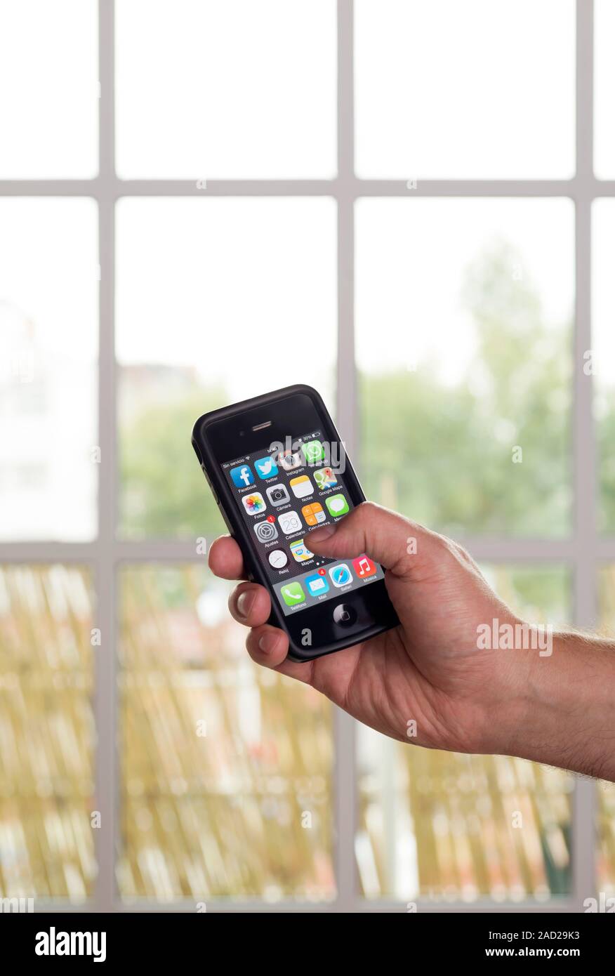 Smartphone use. Hand holding a smartphone displaying start-up icons for several mobile apps. Mobile apps are computer programs that are designed to ru Stock Photo
