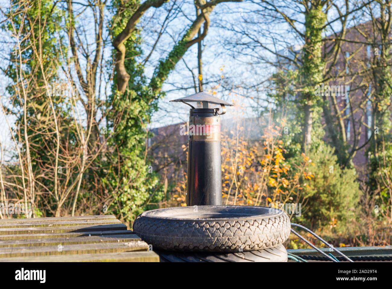 Smoke coming out of a chimney on a narrowboat moored on the Worcester and Birmingham canal in Selly Oak, Birmingham in autumn Stock Photo