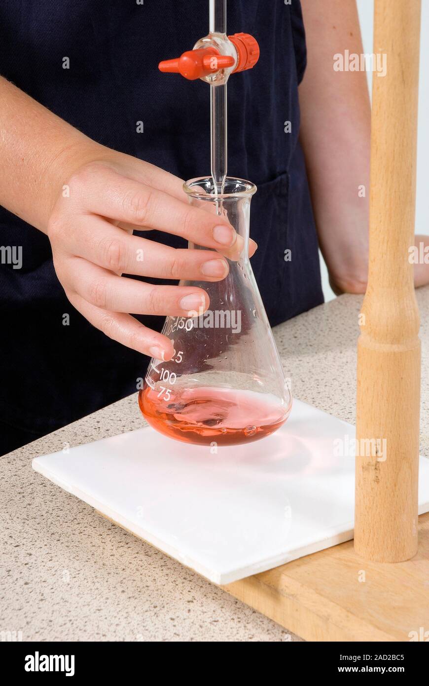 Neutralisation titration. Student using a burette (top) to slowly add