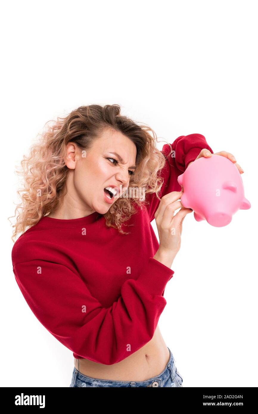 cheeky attractive girl with a piggy bank in hands on a white studio background. Stock Photo