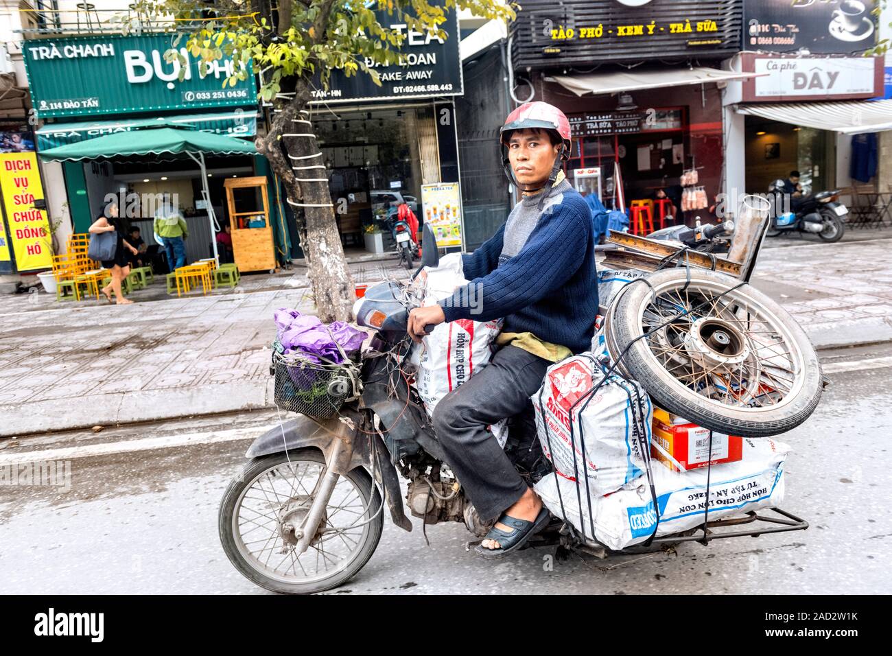 Vietnamese man on moped with bike wheel hires stock photography and
