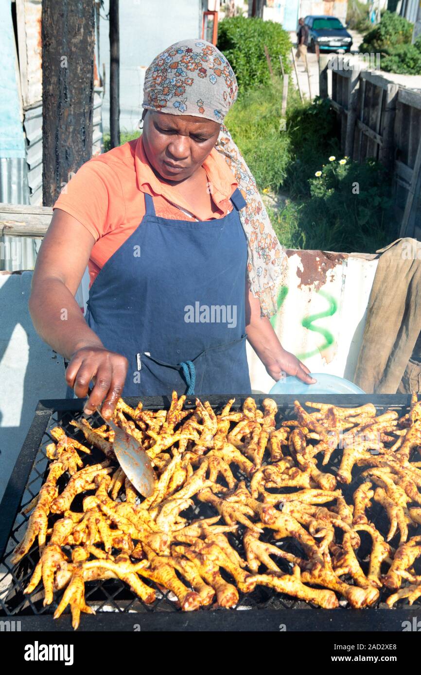 A woman barbecues chickens' feet. Photographed in Khayelitsha Township