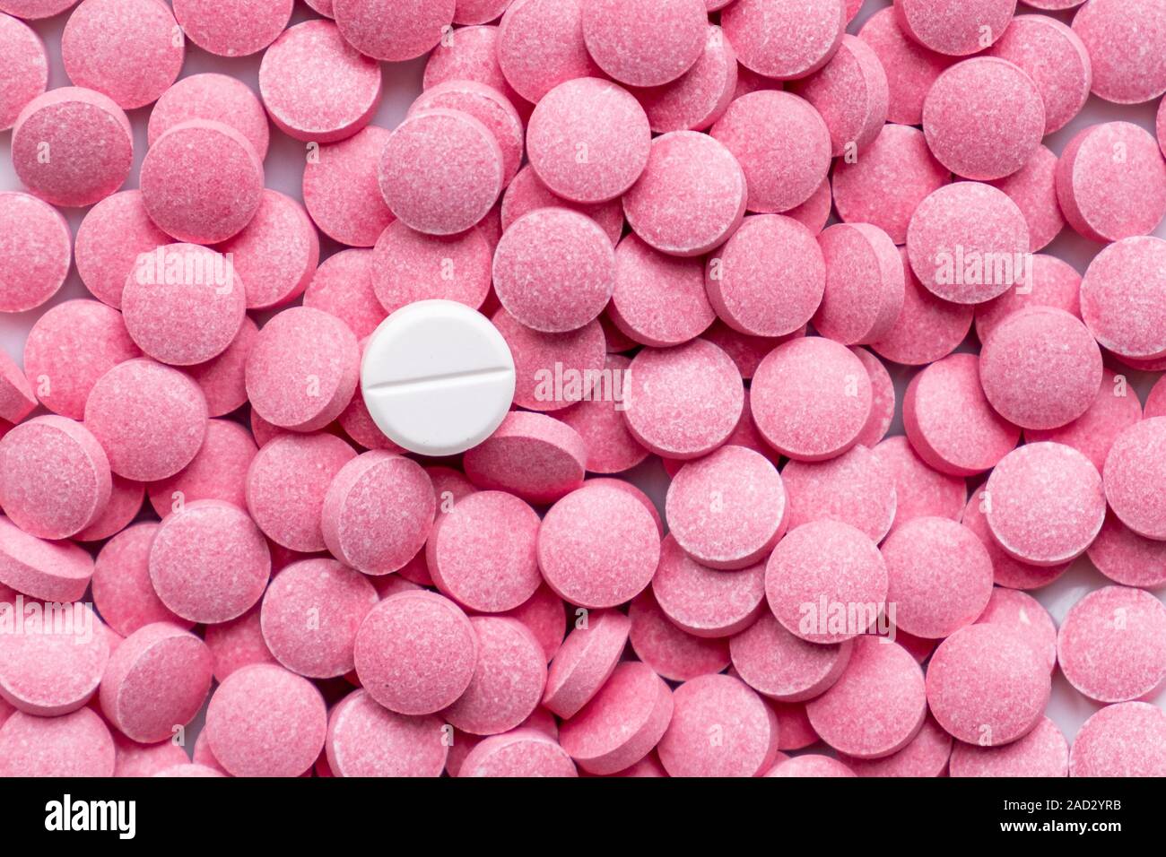 Pile of pink pills and around a white one. Medication, self-treatment or placebo concept: one tablet is different from the lot of others Stock Photo