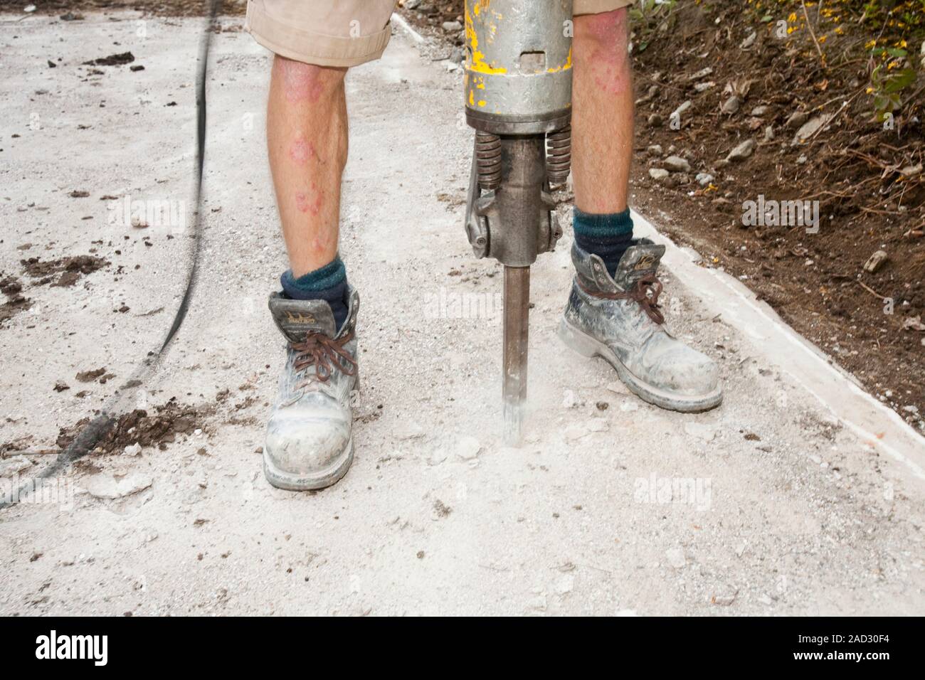 A builder using a jack hammer to break up concrete foundations Stock