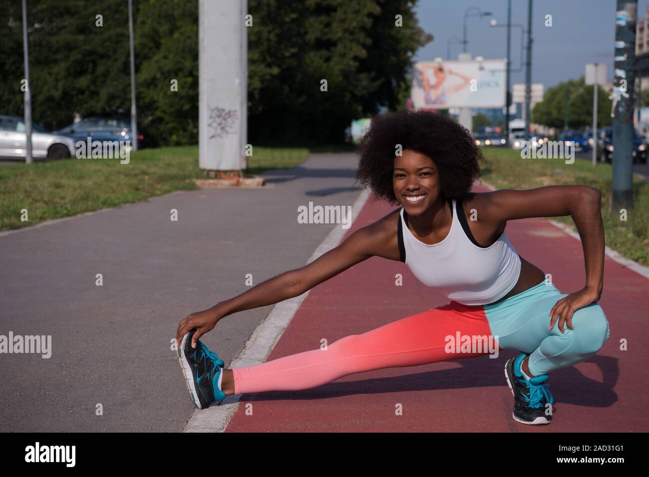 Portrait of sporty young african american woman stretching outdoors ...