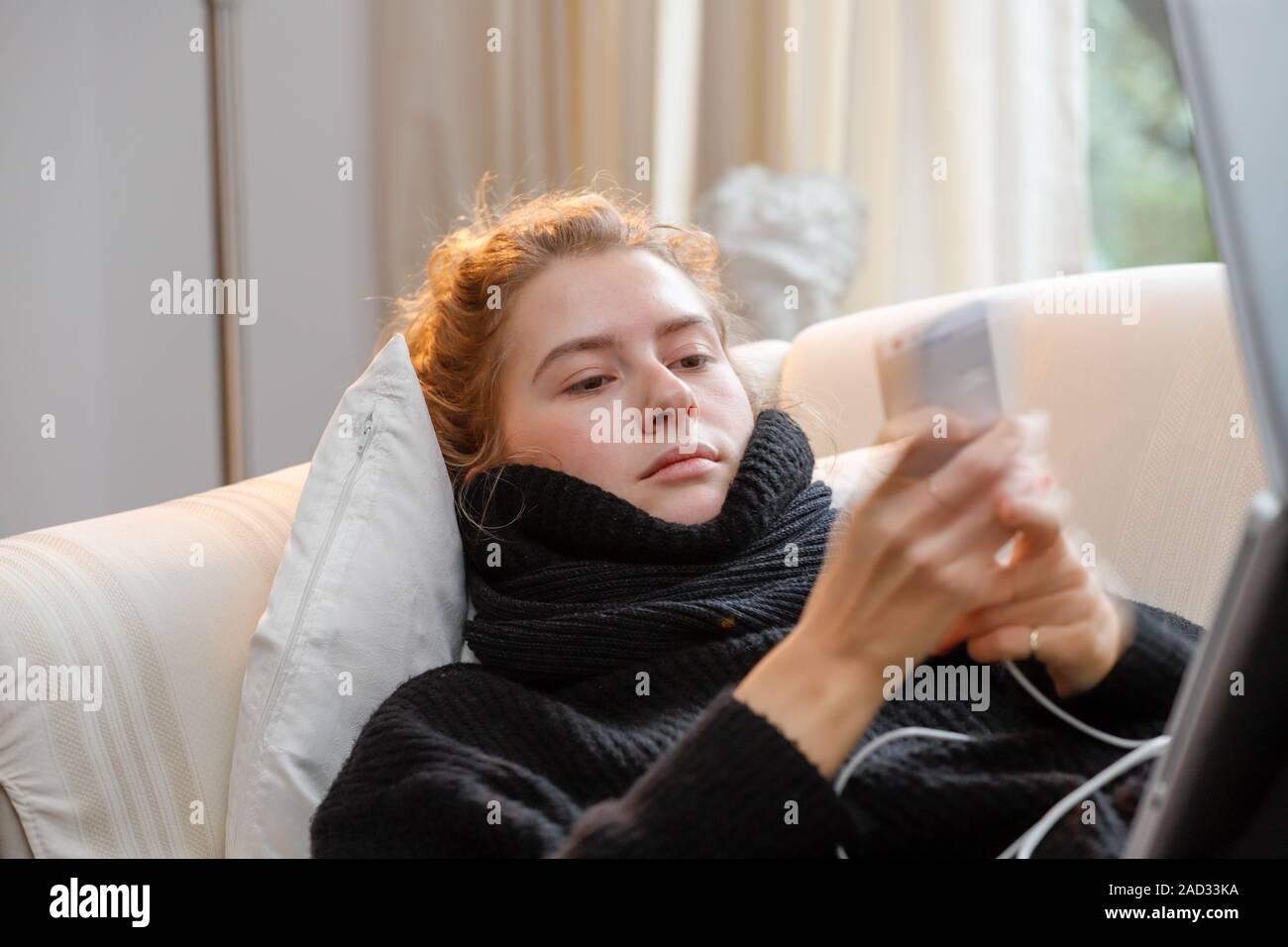 Young attractive law student on a sofa, using notebook and smartphone. Stock Photo