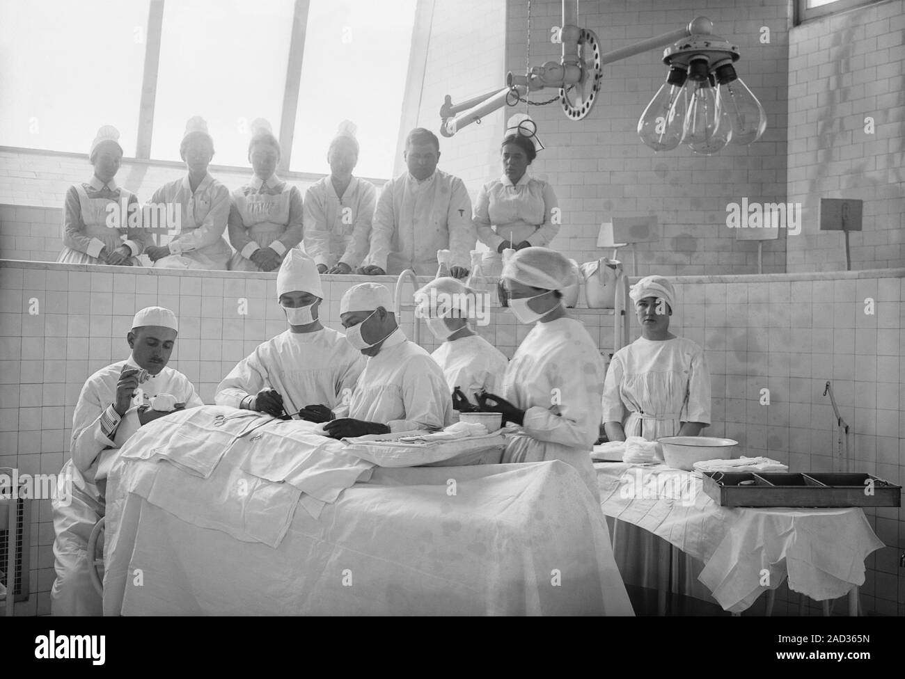 Surgical lesson. Early 20thcentury surgical theatre with surgeons
