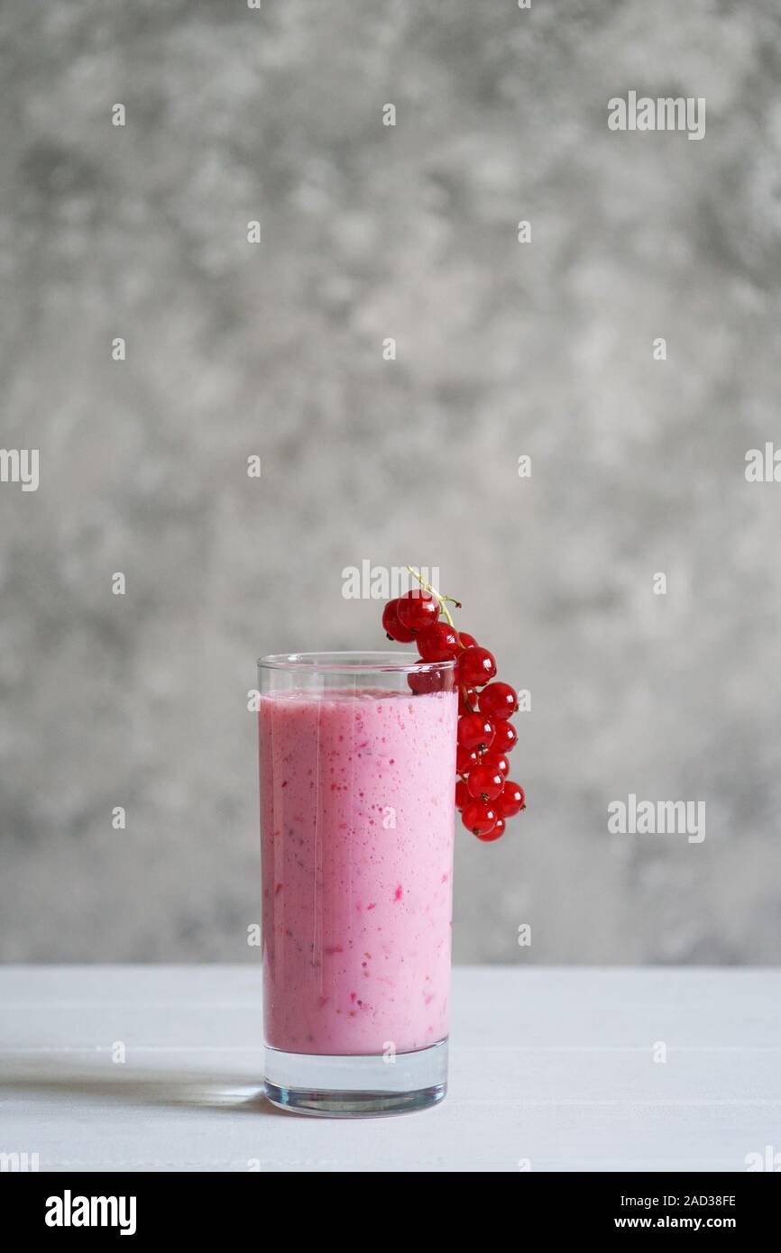 homemade redcurrant smoothie or red currant milkshake in drink glass on table, vertical background with copy space Stock Photo