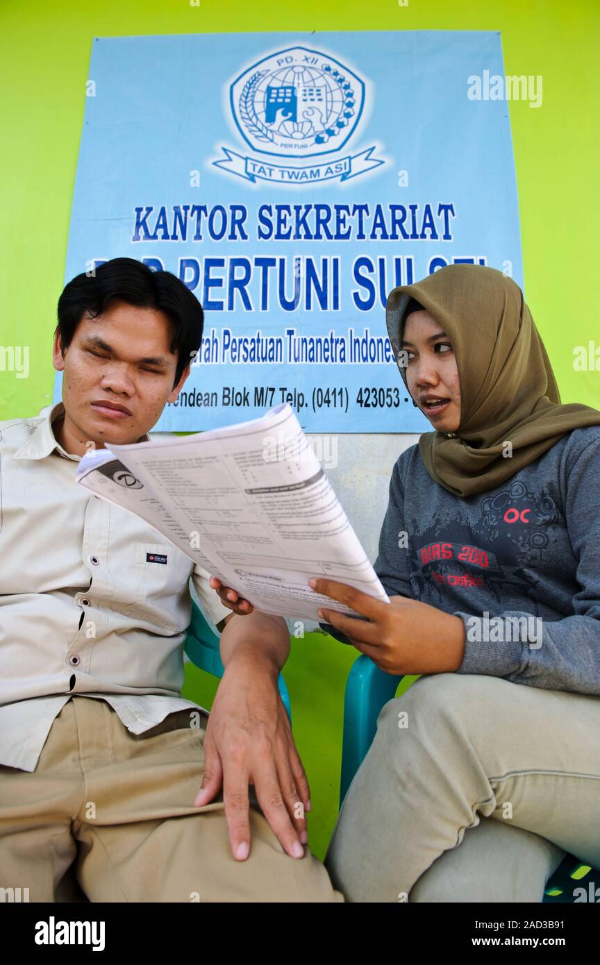 A volunteer reading university course material to a blind man