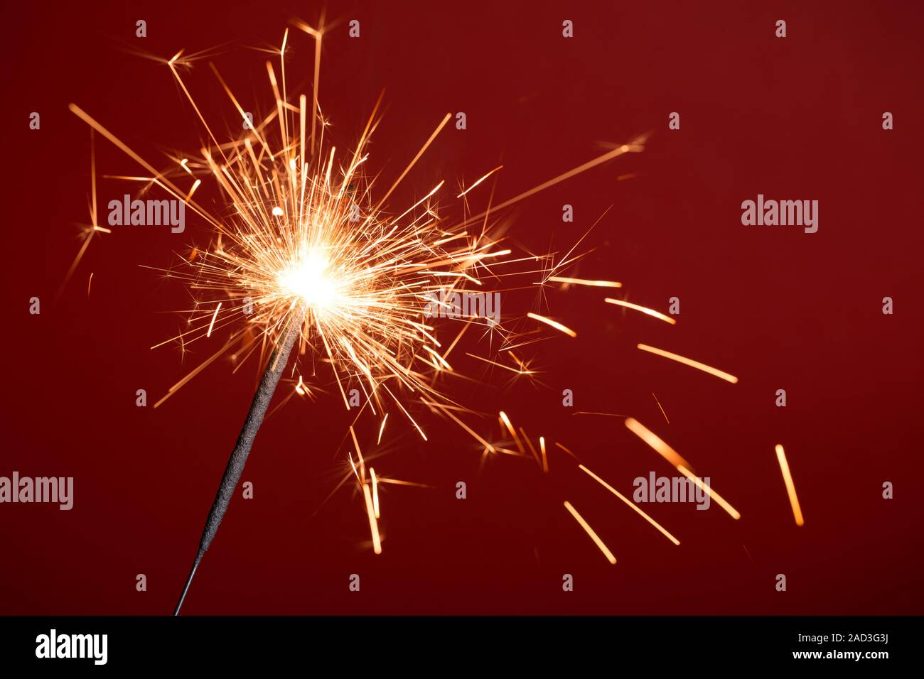 Burning sparkler on red background Stock Photo