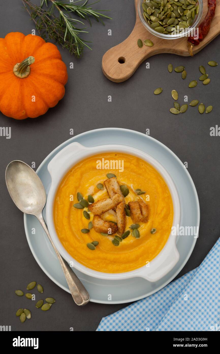 Creamy carrot soup, autumn foods. Spicy, roasted vegetable soup in bowl. Dark background. Stock Photo